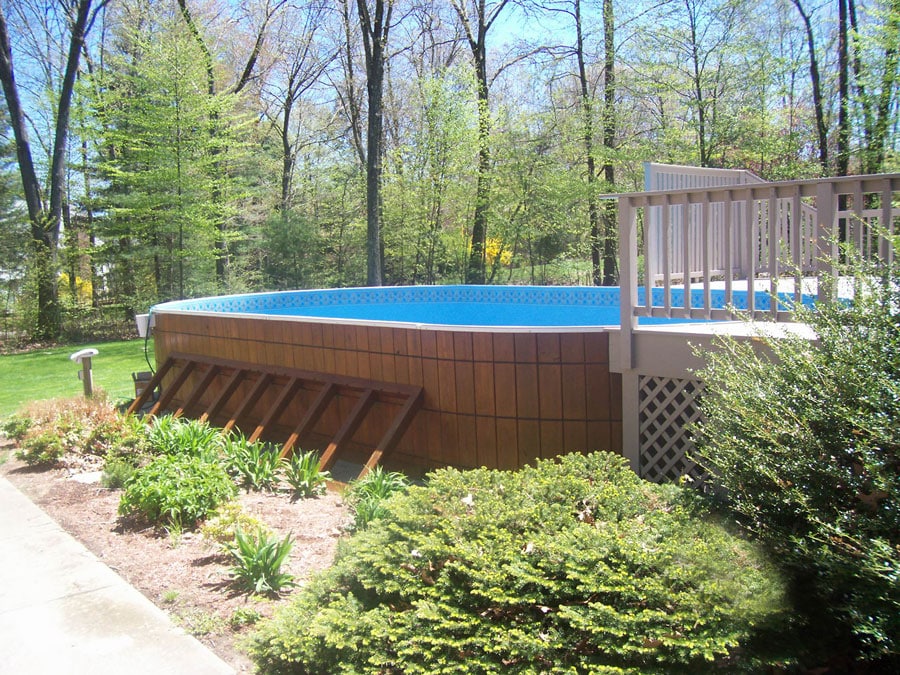 wooden oval above ground pool with wooden patio
