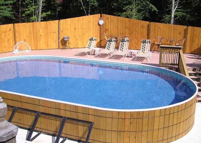 wooden oval above ground pool with wood deck and fencing