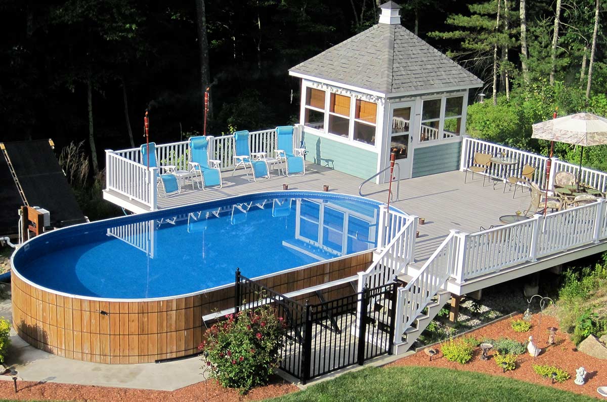 wooden oval above ground pool with deck and cabana