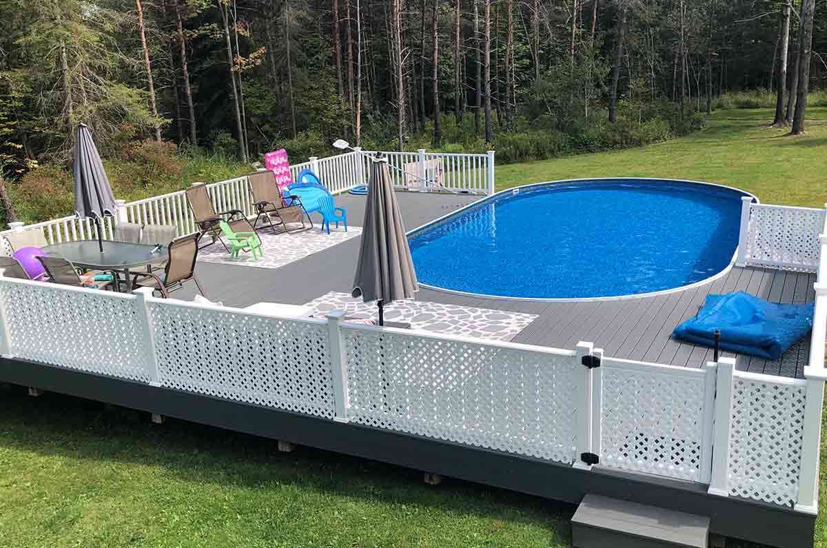 wooden oval above ground pool with a large deck