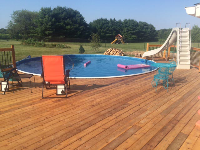 wooden round above ground pool with deck and water slide