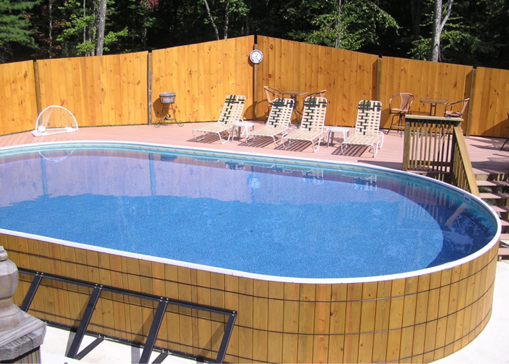 oval wooden above ground pool with deck